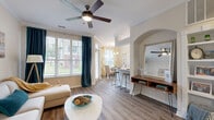 This thoughtfully designed single-floor residence offers a cohesive and comfortable living experience across a well-utilized floor plan. The open-concept living and dining area serves as the heart of the home, featuring warm wood-style flooring, crown molding, and ceiling fans throughout. Large windows flood the space with abundant natural light, while elegant teal drapes add a pop of color. An arched architectural accent wall adds character to the living area, which flows seamlessly into the dining space, illuminated by a stylish chandelier and framed by views of the outdoors.

The galley-style kitchen is efficiently designed with white cabinetry, stone-look countertops, stainless steel appliances, and a dual-basin sink — offering both functionality and a clean aesthetic. A breakfast bar connects the kitchen to the main living area.

The bedroom is a serene retreat with plush carpet flooring, two windows offering outdoor views, and a ceiling fan. It connects directly to the full bathroom, which features a double-sink vanity with stone countertops, wood-style flooring, and direct access to a dedicated walk-in closet.

Additional highlights include a private in-unit laundry room with a full-size washer and dryer, a dedicated hallway, and an entrance area — providing practical convenience throughout.