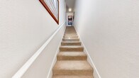 Located at 7017 S Buffalo Dr in Las Vegas, NV, this two-story, 1-bedroom, 2-bathroom residence offers a thoughtfully designed layout spread across two levels. The entry level leads to a carpeted staircase framed by clean white walls, setting a bright and welcoming tone throughout.

The main living level features an open-concept kitchen and living room with rich hardwood-style flooring. The kitchen is equipped with dark espresso cabinetry, stainless steel appliances including a refrigerator, range, and microwave, and a white countertop peninsula that doubles as a breakfast bar. The living room flows seamlessly from the kitchen and opens to a private balcony through a sliding glass door, offering outdoor views and natural light. A ceiling fan adds comfort to the space.

The generously sized primary bedroom features plush carpet, a ceiling fan, a large window for natural light, and access to two dark-paneled doors leading to the closet and en-suite bathroom. The bathroom includes a dual-sink vanity with dark cabinetry and white countertops, complemented by large-format tile flooring. A second full bathroom serves additional needs.

A dedicated laundry room houses a full-size washer and dryer, adding everyday convenience to this well-rounded Las Vegas residence.