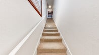 Located at 7017 S Buffalo Dr in Las Vegas, NV, this two-story, 1-bedroom, 2-bathroom residence offers a thoughtfully designed layout spread across two levels. The entry level leads to a carpeted staircase framed by clean white walls, setting a bright and welcoming tone throughout.

The main living level features an open-concept kitchen and living room with rich hardwood-style flooring. The kitchen is equipped with dark espresso cabinetry, stainless steel appliances including a refrigerator, range, and microwave, and a white countertop peninsula that doubles as a breakfast bar. The living room flows seamlessly from the kitchen and opens to a private balcony through a sliding glass door, offering outdoor views and natural light. A ceiling fan adds comfort to the space.

The generously sized primary bedroom features plush carpet, a ceiling fan, a large window for natural light, and access to two dark-paneled doors leading to the closet and en-suite bathroom. The bathroom includes a dual-sink vanity with dark cabinetry and white countertops, complemented by large-format tile flooring. A second full bathroom serves additional needs.

A dedicated laundry room houses a full-size washer and dryer, adding everyday convenience to this well-rounded Las Vegas residence.
