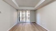 Located on the 11th floor at 140 Main St W in downtown Hamilton, this one-bedroom, two-bathroom condo offers a well-designed layout with contemporary finishes throughout. Light hardwood-style flooring flows seamlessly across the entire unit, complementing the neutral grey palette that creates a clean, modern aesthetic.

The open-concept kitchen is outfitted with rich dark-toned cabinetry, white countertops, a subway tile backsplash, and a full suite of stainless steel appliances including a refrigerator, electric range, microwave, and dishwasher. The kitchen opens directly to the combined dining and living area, which is bathed in natural light from large floor-to-ceiling windows and sliding glass doors that lead to the private balcony.

The spacious primary bedroom features a tray ceiling, generous proportions, and its own access to the outdoors through sliding glass doors. A dedicated den provides flexible space suitable for a home office or additional sleeping area. The unit includes two well-appointed bathrooms — one with a soaker tub and shower combination and a stone-topped vanity, and a second powder-style bathroom with a clean, minimalist design. In-suite laundry and a dedicated closet round out this efficiently planned urban residence.
