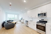 Located at 3309 Liberty Avenue in North Bergen, NJ, this well-appointed one-bedroom, one-bathroom residence offers a thoughtfully designed single-floor layout with a clean, modern aesthetic throughout. Light hardwood flooring flows seamlessly across the living areas, complementing the bright white walls and recessed lighting that give the space an airy, contemporary feel.

The open-concept kitchen and living area serves as the heart of the home. The kitchen is outfitted with high-gloss white cabinetry extending to the ceiling, sleek white countertops, a full suite of stainless steel appliances including a gas range, built-in microwave, dishwasher, and refrigerator. The adjoining living room benefits from a large window offering open outdoor views, filling the space with natural light.

The generously sized bedroom is a comfortable retreat, featuring recessed lighting, a large window with scenic views, and light hardwood flooring. Three closets throughout the unit provide abundant storage, including a sizable walk-in style closet with chrome hanging rods.

The bathroom is elegantly finished with large-format marble-style tile surrounding the soaking tub and shower, a modern white vanity with an undermount sink, and a mirrored medicine cabinet. A dedicated in-unit laundry room with a full-size washer and dryer adds everyday convenience to this polished North Bergen residence.