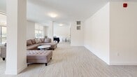 Located at 20142 53A Avenue in Langley, BC, this single-floor amenity space offers a clean, versatile layout well-suited for a variety of uses. The open-plan living room is finished with neutral-toned carpeting and crisp white walls, creating a bright and welcoming atmosphere throughout.

Large windows and a sliding glass door along one wall flood the space with natural light while offering views of the surrounding outdoor area, including a patio and the broader Langley streetscape. The generous proportions of the room allow for flexible furniture arrangements, and portable fabric room dividers are present, enabling the space to be sectioned off as needed for different activities or gatherings.

A structural column near the centre of the room adds an architectural element while subtly defining different zones within the open floor plan. Flush ceiling-mounted light fixtures provide consistent ambient lighting. A dedicated entrance door with a label and a secondary utility door are visible, along with an intercom panel, suggesting the space is part of a larger residential or mixed-use building. A separate area toward the back accommodates a table and chairs, ideal for meetings or dining. The overall ambiance is modern, minimal, and adaptable, making this a highly functional communal space.