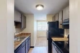 Located at 508 Ivy Ridge Rd in Syracuse, NY, this one-bedroom, one-bathroom residence offers a well-organized single-floor layout that makes efficient use of its compact footprint. The galley-style kitchen is thoughtfully equipped with dark wood cabinetry, granite-toned countertops, a stainless steel sink, and black appliances including a refrigerator and electric range. Light hardwood-style flooring runs through the kitchen, which opens via a hallway toward the rest of the unit. The living room is generously proportioned, featuring neutral carpet, warm beige walls, a baseboard heating system, and a sliding glass door fitted with vertical blinds that provides natural light and outdoor access to a latticed balcony area. The spacious bedroom offers plush carpeting, a large window with tree-lined views, baseboard heating, and notable storage with two side-by-side bi-fold closets. A dedicated hallway connects the main living areas and includes additional closet space for added convenience. Throughout the unit, the neutral color palette and clean finishes create a calm, functional ambiance well suited for comfortable everyday living.