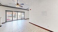 Located in the heart of downtown Saint Louis on Olive Street, this single-floor unit offers a thoughtfully designed layout that blends modern finishes with industrial-style character. Light-toned wood-look tile flooring flows throughout, complemented by rich dark wood baseboards that create a striking contrast against the crisp white walls.

The open kitchen and dining area is a standout feature, showcasing rich dark wood cabinetry with brushed nickel hardware, a stainless steel farmhouse sink with a professional-style faucet, and a full suite of stainless steel appliances including a range, microwave, and dishwasher. A breakfast bar provides additional counter space and a casual dining option, while pendant lighting and recessed fixtures illuminate the area. Large glass sliding doors lead to an outdoor balcony, filling the space with natural light and offering views of the surrounding cityscape.

The main living area features exposed industrial piping along the ceiling, a ceiling fan, and track lighting, lending the space an authentic urban loft aesthetic. A bedroom space is accessed through distinctive dark-framed sliding barn-style doors with frosted glass panels, adding both privacy and architectural interest.

The bathroom is elegantly finished with dual vessel sinks set on a dark wood double vanity, large-format tile flooring, and a combined soaking tub and glass-enclosed shower, creating a refined and functional retreat.