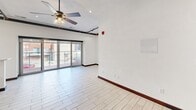 Located in the heart of downtown Saint Louis on Olive Street, this single-floor unit offers a thoughtfully designed layout that blends modern finishes with industrial-style character. Light-toned wood-look tile flooring flows throughout, complemented by rich dark wood baseboards that create a striking contrast against the crisp white walls.

The open kitchen and dining area is a standout feature, showcasing rich dark wood cabinetry with brushed nickel hardware, a stainless steel farmhouse sink with a professional-style faucet, and a full suite of stainless steel appliances including a range, microwave, and dishwasher. A breakfast bar provides additional counter space and a casual dining option, while pendant lighting and recessed fixtures illuminate the area. Large glass sliding doors lead to an outdoor balcony, filling the space with natural light and offering views of the surrounding cityscape.

The main living area features exposed industrial piping along the ceiling, a ceiling fan, and track lighting, lending the space an authentic urban loft aesthetic. A bedroom space is accessed through distinctive dark-framed sliding barn-style doors with frosted glass panels, adding both privacy and architectural interest.

The bathroom is elegantly finished with dual vessel sinks set on a dark wood double vanity, large-format tile flooring, and a combined soaking tub and glass-enclosed shower, creating a refined and functional retreat.