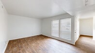 This two-story home is efficiently laid out across two floors of nearly equal size, accommodating four bedrooms, two bathrooms, a living room, and a kitchen. The ground floor features wood-look flooring throughout the main living and kitchen areas, with neutral white walls creating a bright, clean atmosphere. The living room receives natural light through large windows fitted with horizontal blinds, while a secondary room on this level features track lighting and similar wood-look flooring. The compact kitchen is equipped with white cabinetry, speckled stone countertops, a stainless steel refrigerator, and a dishwasher.

The upper floor houses the bedrooms, which are finished with plush carpet and ceiling fans. The primary bedroom offers a comfortable footprint with a window and closet space. Additional bedrooms include built-in shelving for storage. The bathrooms feature speckled stone countertops, white vanity cabinetry, mirrored medicine cabinets, and a tiled shower-tub combination. Hallways connect the rooms efficiently, and two staircases provide access between floors, contributing to practical circulation throughout the home.