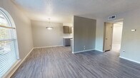 Located at 5418 N Meridian Ave in Oklahoma City, Oklahoma, this single-floor unit offers a clean, modern aesthetic throughout. The open living and dining area is anchored by durable wood-look vinyl plank flooring in a cool gray tone, neutral painted walls, and a textured ceiling. A stylish pendant light fixture highlights the dining area, which connects seamlessly to the kitchen via a half-wall partition. The galley-style kitchen is well-equipped, featuring gray lower and upper cabinetry, white countertops, a white electric range, and ample storage on both sides of the corridor layout. Natural light filters into the spacious living room through an arched window, creating a bright and welcoming atmosphere. The bedrooms are comfortably sized, each with wood-look flooring, neutral walls, and windows that allow natural light. The primary bathroom includes a single-sink vanity with white countertop, a full tub and shower combination, and dark overhead cabinetry for additional storage. A second bathroom provides a toilet, vanity, and dark upper cabinetry. Throughout the unit, consistent finishes and a cohesive neutral color palette contribute to a clean, move-in-ready environment.