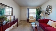 Located in the Riverdale neighborhood of Memphis, Tennessee, this single-floor residence offers a well-organized and functional layout throughout. The living room provides a welcoming atmosphere, featuring plush carpeting, large windows that invite natural light, and ample space for seating. An elegant chandelier-lit dining area adjoins the living space, complete with a glass-top dining table and a pass-through view into the kitchen, creating an open, connected feel. The kitchen is equipped with a range, microwave, and generous cabinet storage, and is finished with textured wallcovering. A notable convenience is the in-unit washer and dryer, situated within the kitchen area alongside a window for added light. Both bedrooms are carpeted and comfortably sized, each featuring tufted headboards and warm, neutral tones. The primary bedroom includes a spacious walk-in closet outfitted with wire shelving and hanging rods for organized storage. The full bathroom features a tub-shower combination, patterned wallcovering, and a vanity with ample counter space. Textured ceilings are present throughout the home, contributing to the overall character of the space.