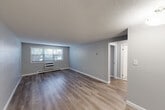 Located at 8 Old Colony Ln in Arlington, MA, this single-floor, 2-bedroom, 1-bathroom residence offers a clean, functional layout with a cohesive design throughout. The living room is the heart of the home, featuring light-toned hardwood-style flooring, neutral gray walls, textured ceilings, and a window unit for climate control alongside baseboard heating. A window allows natural light to fill the space, creating a bright and open feel. The kitchen is efficiently designed with white cabinetry, granite-look countertops, a stainless steel sink, and white appliances including a refrigerator and dishwasher, all complemented by light wood flooring. The primary bedroom is a well-proportioned room benefiting from dual windows that invite abundant natural light and outdoor views, also featuring baseboard heating and the same consistent hardwood-style flooring. The second bedroom is similarly finished with clean walls and matching floors. The bathroom is tiled in neutral tones with a full bathtub with shower, toilet, and a window for natural ventilation. With four closets distributed throughout the unit and a connecting hallway, storage and flow are thoughtfully addressed in this well-maintained Arlington residence.
