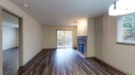 This single-floor residence offers a cohesive and functional layout enhanced by dark hardwood-style flooring that runs consistently throughout the space. The open living area serves as the centerpiece of the unit, anchored by a gas fireplace with a clean surround and framed by a sliding glass door that opens to a private patio, providing views of lush greenery and ample natural light.

The kitchen is well-equipped with dark espresso cabinetry, light countertops, a tile backsplash, and a full suite of stainless steel appliances including a refrigerator, electric range, microwave, and dishwasher. A peninsula counter provides additional workspace and a natural division between the kitchen and dining area, which is illuminated by a pendant light fixture.

The bedrooms are generously sized, each featuring the same hardwood-style flooring, neutral walls, and windows for natural light. One bedroom includes a ceiling fan. The primary ensuite bathroom features a dual-sink vanity with dark cabinetry, a large mirror, and open shelving. A secondary full bathroom includes a soaking tub, window, and matching dark vanity cabinetry, maintaining a consistent design aesthetic throughout.
