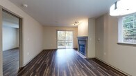 This single-floor residence offers a cohesive and functional layout enhanced by dark hardwood-style flooring that runs consistently throughout the space. The open living area serves as the centerpiece of the unit, anchored by a gas fireplace with a clean surround and framed by a sliding glass door that opens to a private patio, providing views of lush greenery and ample natural light.

The kitchen is well-equipped with dark espresso cabinetry, light countertops, a tile backsplash, and a full suite of stainless steel appliances including a refrigerator, electric range, microwave, and dishwasher. A peninsula counter provides additional workspace and a natural division between the kitchen and dining area, which is illuminated by a pendant light fixture.

The bedrooms are generously sized, each featuring the same hardwood-style flooring, neutral walls, and windows for natural light. One bedroom includes a ceiling fan. The primary ensuite bathroom features a dual-sink vanity with dark cabinetry, a large mirror, and open shelving. A secondary full bathroom includes a soaking tub, window, and matching dark vanity cabinetry, maintaining a consistent design aesthetic throughout.