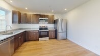 This two-story residence offers a thoughtfully designed layout spread across two evenly sized floors, providing a comfortable and functional living environment. Light-toned hardwood-style flooring flows consistently throughout the home, creating a cohesive and warm aesthetic.

The main floor encompasses a combined kitchen and living area. The kitchen is outfitted with rich dark wood cabinetry, granite countertops, and a full suite of stainless steel appliances, including a range, over-the-range microwave, and French door refrigerator. The living room is bright and open, benefiting from sliding glass doors that lead to a private balcony overlooking the surrounding neighborhood, complemented by a ceiling fan overhead.

Upstairs, two well-proportioned bedrooms offer comfortable retreats, each featuring hardwood-style flooring, ceiling fans, and clean white walls. The spacious primary bedroom provides ample room for furnishings, while the second bedroom includes a window that brings in natural light. A dedicated walk-in closet with adjustable wire shelving adds practical storage.

The two bathrooms are finished with granite-topped dark wood vanities and brushed nickel fixtures. One bathroom features a full tub-shower combination with grab bars. A dedicated laundry area and hallway complete the home's practical offerings, making this a well-rounded and move-in-ready residence.