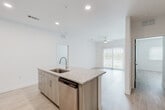 Located at 21101 Panama City Beach Pkwy in Panama City Beach, Florida, this well-appointed single-floor unit offers a bright, modern interior with a clean, contemporary design. The open-concept layout seamlessly connects the kitchen and living area, creating an airy and functional living space. The kitchen is a standout feature, equipped with stainless steel appliances including a refrigerator, range, microwave, and dishwasher, complemented by light wood-tone cabinetry that extends to the ceiling for ample storage. A central island with granite countertops and an integrated sink adds both style and practicality. Light wood-style flooring flows consistently throughout the unit, enhancing the bright and cohesive aesthetic. The living area benefits from natural light through large sliding glass doors fitted with vertical blinds, and a ceiling fan ensures comfort year-round. The bedrooms are generously sized, each featuring ceiling fans and windows with blinds that allow for natural light and privacy. The bathroom is finished with granite countertops, a lighted vanity mirror, and a full tub-shower combination. A dedicated laundry area houses a full-size washer and dryer with overhead shelving. Recessed lighting throughout adds a polished, modern touch to this move-in-ready space.