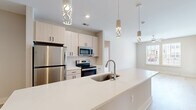 Located at 98 Northwood Blvd in Pittsboro, NC, this single-floor, 3-bedroom, 2-bathroom home offers a clean, contemporary design with an efficient and well-appointed layout. The open-concept kitchen is a standout feature, showcasing a large center island with a quartz countertop, undermount sink, and stylish pendant lighting. Light wood cabinetry, a white subway tile backsplash, and a full suite of stainless steel appliances—including a refrigerator, range, and microwave—complete the modern aesthetic. Light hardwood-style flooring flows seamlessly from the kitchen into the living room, which is brightened by large windows and finished with a ceiling fan. The bedrooms are carpeted for comfort, with large windows allowing ample natural light; the primary bedroom connects directly to an en suite bathroom. The bathrooms feature clean, minimalist finishes, including a wide-format light wood vanity with quartz countertop, a large framed mirror, and a soaking tub with crisp white tile surround. Neutral warm-toned walls and consistent trim work throughout the home create a cohesive and inviting atmosphere well-suited for modern living.