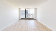 This fourth-floor unit at 129 Wellington Street in Brantford offers a well-organized layout across a comfortable single floor, comprising two bedrooms, one bathroom, and a living area. Consistent light wood laminate flooring runs throughout the unit, lending a cohesive and clean aesthetic to every room.

The living room is a bright, open space anchored by large sliding glass doors that open to a balcony, filling the area with natural light and providing views of the surrounding Brantford cityscape. Baseboard heating runs beneath the windows, and the textured ceiling adds subtle dimension to the space.

The primary bedroom is a well-proportioned room featuring a wide window that frames city views and allows ample daylight. The second bedroom is similarly finished, with its own window, a built-in sliding closet, and the same warm wood flooring. Both rooms maintain a clean, neutral palette with white walls and white baseboards.

The bathroom is finished with classic white subway tile surrounding the soaker tub and shower combination, complemented by grey floor tile and a light stone-topped vanity, offering a timeless and functional design.

Overall, the unit presents a bright, modern, and efficiently designed living space suited for everyday comfort in a convenient Brantford location.