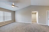 Located at 3300 N McDonald St in McKinney, TX, this one-bedroom, one-bathroom unit offers a well-designed single-floor layout with a variety of functional living spaces. The combined living and dining area is the heart of the home, featuring striking vaulted ceilings, neutral gray walls, plush carpeting, and a ceiling fan with light. A large window dressed with vertical blinds fills the space with natural light, while an open passageway leads seamlessly to the rest of the unit. The kitchen is equipped with warm wood cabinetry, white appliances, tile flooring, and a peninsula breakfast bar with a sink—ideal for casual dining and food prep. A pendant light above the bar adds a stylish touch. The bedroom is a comfortable, carpeted retreat with its own ceiling fan, a window for natural light, and direct access to a generously sized walk-in closet outfitted with wire shelving. The full bathroom features rich hardwood-style flooring, a wood-toned vanity with a white countertop, a mirror, and clean white walls. Additional conveniences include a dedicated laundry area and utility room. The overall aesthetic is clean, neutral, and move-in ready.