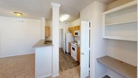 This single-floor residence offers a thoughtfully designed layout that balances comfort and functionality throughout. The open-concept living area is bright and welcoming, featuring plush carpeted flooring, a ceiling fan with light fixture, and multiple windows dressed with blinds that frame views of the surrounding neighborhood. Crown molding and clean neutral walls add a polished touch to the space.

The kitchen is efficiently designed with warm honey-toned cabinetry, laminate countertops, a breakfast bar peninsula with decorative columns, and wood-look flooring. White appliances, including a refrigerator, electric range, and microwave, are neatly integrated. A built-in desk area and open shelving provide additional utility adjacent to the living space.

The bedrooms are carpeted and well-lit, each equipped with ceiling fans and windows that bring in natural light. One bedroom features a reach-in closet, while another benefits from a window seat, adding a charming architectural detail. A spacious walk-in closet with wire shelving and hanging rods offers generous storage capacity.

The bathrooms are practical and clean in design. The primary bathroom includes a double-sink vanity with oak cabinetry, a large mirror, and wood-look flooring. A separate tub-shower combination with white tile surround and a chrome curtain rod completes the bathing area, providing a straightforward and functional finish.