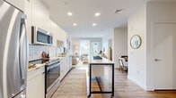 Unit 204 at 50 Salt St in Revere, MA is a thoughtfully designed one-bedroom, one-bathroom residence that maximizes its efficient footprint with a clean, contemporary aesthetic. The open-concept layout seamlessly connects the kitchen and living room, creating an airy, functional living space bathed in natural light.

The kitchen is a standout feature, outfitted with sleek white cabinetry, a white geometric tile backsplash, stainless steel appliances including a refrigerator, range, microwave, and dishwasher, and light quartz countertops. A mobile island with a white top adds flexible prep and dining space. Warm hardwood flooring runs throughout the main living areas.

The living room is bright and inviting, anchored by a large sliding glass door with outdoor views and ample natural light. The bedroom is a calm retreat with a dedicated window, generous closet, and direct access to the rest of the unit via hallway. The bathroom features marble-look tile flooring, a full soaking tub with tiled surround, and a wood-toned vanity with clean white countertops. Recessed lighting throughout and neutral white walls lend the entire unit a modern, cohesive feel well-suited for comfortable everyday living.