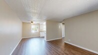 This well-designed 790 square foot apartment in El Cajon, CA offers a harmonious blend of comfort and functionality. The space features two bedrooms, including a generously sized primary bedroom of 180 square feet, and one bathroom. The kitchen is a highlight, boasting white cabinetry, granite countertops, and modern appliances, all complemented by durable wood-like flooring.

The living areas showcase a mix of plush carpeting and continuation of the wood-like flooring, creating distinct zones within the open layout. Large windows and a sliding glass door in one room provide ample natural light and access to an outdoor area, enhancing the sense of space.

Both bedrooms are carpeted for comfort, with the primary bedroom featuring a spacious closet with sliding doors and built-in shelving. The bathroom, while compact, offers a clean and functional design with a shower/tub combination.

Ceiling fans in multiple rooms provide air circulation, while an air conditioning unit is visible in one room for additional climate control. The neutral color palette throughout allows for easy personalization, making this apartment a versatile canvas for various decorating styles.