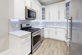 Located at 35-09 191st Street in Flushing, NY, this two-floor home presents a thoughtfully renovated interior combining modern finishes with classic architectural details. The kitchen is outfitted with crisp white shaker cabinetry, marble-look quartz countertops, a marble tile backsplash with under-cabinet LED lighting, and stainless steel appliances including a gas range and built-in microwave. Light wood-look flooring completes the bright, clean aesthetic of this culinary space.

The bedrooms are carpeted throughout and finished with neutral tones, crown molding, and recessed lighting paired with ceiling fans. Several rooms feature wall-mounted mini-split units for individualized climate control. Natural light flows through multi-pane windows with views of the surrounding neighborhood. One upper-floor room showcases charming sloped ceilings, adding architectural character.

The bathrooms are elegantly finished with large-format marble-look wall tiles, basketweave mosaic tile flooring, and white cabinetry topped with veined marble countertops. One bathroom includes a glass-enclosed tub and shower combination, while another offers a separate glass shower enclosure. Gold-tone fixtures and a natural light window add refined detail throughout the bathrooms, contributing to the home's polished overall presentation.