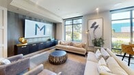Located at 16101 Murphy Ave in Irvine, CA, this single-floor community lounge at The Murphy is a well-appointed gathering space designed for both relaxation and social engagement. The open-plan layout is unified by light hardwood flooring and recessed lighting throughout, creating a bright and welcoming atmosphere.

The space is organized into several distinct functional zones. A comfortable lounge area anchors one side of the room, featuring plush neutral-toned sofas and accent chairs arranged around a sculptural wood-stump coffee table. Large floor-to-ceiling windows flood this area with natural light and offer views of the surrounding greenery. A striking feature wall displaying The Murphy's branded signage serves as a focal point, flanked by a sleek dark-finish credenza with decorative accents.

Adjacent to the lounge, a full-size billiards table with a vivid teal felt surface takes center stage, accompanied by a wet bar with sink and cabinetry along the back wall — ideal for entertaining. Further into the space, a dedicated media and dining zone features wall-mounted screens, a long communal table with bar-height seating, and accent chairs in rich jewel tones, providing a versatile area for presentations or casual dining. The overall ambiance is modern and sophisticated, blending comfort with upscale design throughout.