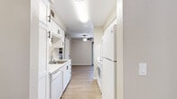 Located in Citrus Heights, CA, this one-bedroom, two-bathroom residence offers a thoughtfully designed single-floor layout with a versatile den, in-unit laundry, and a private patio. Light-toned luxury vinyl plank flooring flows throughout, complementing the neutral warm-gray palette found in every room. The galley-style kitchen is outfitted with white shaker cabinetry featuring matte black hardware, white appliances including a refrigerator and dishwasher, a stainless steel sink, and light countertops, opening toward the living area. The spacious living room features a ceiling fan and built-in shelving, creating an open, airy feel. A dedicated den provides flexible space ideal for a home office or additional living area. The generously sized primary bedroom includes natural light from a window with outdoor views, while the hallway features a built-in vanity with white drawers and ample closet access across three closets. Both bathrooms are clean and functional, with one featuring a tub-shower combination and a window for natural light. The dedicated laundry room accommodates a full-size washer and dryer side by side. Textured ceilings and consistent trim work tie the interior together, while the private patio extends the living space outdoors.