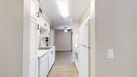 Located in Citrus Heights, CA, this one-bedroom, two-bathroom residence offers a thoughtfully designed single-floor layout with a versatile den, in-unit laundry, and a private patio. Light-toned luxury vinyl plank flooring flows throughout, complementing the neutral warm-gray palette found in every room. The galley-style kitchen is outfitted with white shaker cabinetry featuring matte black hardware, white appliances including a refrigerator and dishwasher, a stainless steel sink, and light countertops, opening toward the living area. The spacious living room features a ceiling fan and built-in shelving, creating an open, airy feel. A dedicated den provides flexible space ideal for a home office or additional living area. The generously sized primary bedroom includes natural light from a window with outdoor views, while the hallway features a built-in vanity with white drawers and ample closet access across three closets. Both bathrooms are clean and functional, with one featuring a tub-shower combination and a window for natural light. The dedicated laundry room accommodates a full-size washer and dryer side by side. Textured ceilings and consistent trim work tie the interior together, while the private patio extends the living space outdoors.