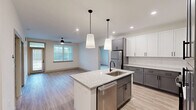 This well-appointed 2-bedroom, 2-bathroom single-story home in Fayetteville, NC offers a thoughtfully designed layout with modern finishes throughout. The open-concept kitchen serves as the heart of the home, showcasing a striking combination of white upper cabinets and gray lower cabinets, granite countertops, a white subway tile backsplash, and a center island with an undermount sink and built-in dishwasher. Pendant lighting and recessed fixtures illuminate the space, which flows seamlessly into the living room—complete with a ceiling fan and natural light from a large window with blinds. Light wood-look flooring runs throughout the main living areas, adding warmth and continuity. Both bedrooms feature plush carpeting and ceiling fans, with each room offering access to its own dedicated closet. The spacious primary bedroom connects to a well-organized walk-in closet equipped with wire shelving on multiple walls. The second bedroom also benefits from a generous walk-in closet with wire rack storage. The bathrooms are finished with granite-topped vanities and matte black hardware accents. A dedicated laundry area and two closets round out the functional layout, making this home as practical as it is polished.