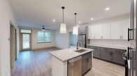 This well-appointed 2-bedroom, 2-bathroom single-story home in Fayetteville, NC offers a thoughtfully designed layout with modern finishes throughout. The open-concept kitchen serves as the heart of the home, showcasing a striking combination of white upper cabinets and gray lower cabinets, granite countertops, a white subway tile backsplash, and a center island with an undermount sink and built-in dishwasher. Pendant lighting and recessed fixtures illuminate the space, which flows seamlessly into the living room—complete with a ceiling fan and natural light from a large window with blinds. Light wood-look flooring runs throughout the main living areas, adding warmth and continuity. Both bedrooms feature plush carpeting and ceiling fans, with each room offering access to its own dedicated closet. The spacious primary bedroom connects to a well-organized walk-in closet equipped with wire shelving on multiple walls. The second bedroom also benefits from a generous walk-in closet with wire rack storage. The bathrooms are finished with granite-topped vanities and matte black hardware accents. A dedicated laundry area and two closets round out the functional layout, making this home as practical as it is polished.