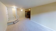 This 2-bedroom, 1-bathroom unit in Ontario offers a practical and well-organized layout across a single floor. The living area is generously proportioned, featuring soft wall-to-wall carpeting that adds warmth underfoot, and is equipped with a ceiling fan to promote air circulation and comfort. Neutral-toned walls throughout create a clean, versatile backdrop suited to a variety of interior styles. A few steps lead up from the entry level into the main living space, adding a subtle sense of transition and definition between areas. The kitchen, open to the living space, is outfitted with dark wood cabinetry providing ample storage, a stainless steel refrigerator, a microwave, and a range, offering everything needed for everyday meal preparation. The layout promotes an easy flow between the kitchen and living areas, making the space feel connected and functional. White trim and baseboards provide a crisp contrast to the warm tones of the carpet and cabinetry. The overall ambiance is cozy and straightforward, designed with practicality in mind while maintaining a comfortable, livable atmosphere throughout.