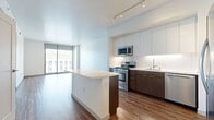 This 700 square foot, one-bedroom apartment in Los Angeles offers a perfect blend of modern design and urban living. The open-concept layout maximizes space, seamlessly integrating the kitchen, living, and dining areas. The kitchen boasts sleek white cabinetry, contrasting dark lower cabinets, stainless steel appliances, and a functional island, all complemented by warm wood flooring.

The spacious 130 square foot bedroom features plush carpeting and large windows that flood the space with natural light. An enviable walk-in closet provides ample storage with built-in shelving and hanging space. The bathroom is a study in contemporary design, with a floating vanity, large mirror, and a combination tub-shower.

Floor-to-ceiling windows in the living area and bedroom offer breathtaking panoramic views of the Los Angeles cityscape, creating a sense of expansiveness in the urban setting. The apartment's neutral color palette and clean lines contribute to its modern aesthetic, while track lighting adds a touch of sophistication. This well-designed space efficiently accommodates all the necessities of city living in a stylish, compact package.