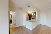 Located in Miami Lakes, FL, this well-appointed one-bedroom, one-bathroom residence offers a thoughtfully designed single-floor layout. The open-concept living and kitchen area serves as the heart of the home, featuring elegant granite countertops on a peninsula island with a built-in sink, rich dark-espresso cabinetry, a tile backsplash, and a full suite of stainless steel appliances including a refrigerator, electric range, and dishwasher. Pendant lighting above the island adds a modern touch, while wood-look flooring flows throughout the main living space, complemented by crown molding for a refined finish. Sliding glass doors with vertical blinds open to a private balcony with outdoor views, filling the living area with natural light. The bedroom is carpeted for comfort and includes a ceiling fan, a window with natural light, and access to a dedicated walk-in closet. The bathroom features a granite-topped dark vanity with an undermount sink and tile flooring, consistent with the home's cohesive design palette. A separate laundry room houses a full-size Whirlpool washer and dryer with overhead shelving. This residence offers a functional and stylish layout suited for comfortable everyday living.