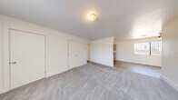 Located at 4801 Iowa in Las Vegas, NV, this two-bedroom, one-bathroom unit offers a clean, functional layout across a single floor. The living room is generously proportioned, featuring soft neutral carpet, crisp white walls, and a large window fitted with vertical blinds that allows natural light to fill the space. The area flows seamlessly toward the kitchen, which is visible in the background and features hard-surface flooring for easy maintenance.

Both bedrooms are carpeted and well-sized, each equipped with windows that bring in natural light. The primary bedroom is notably spacious and includes access to two closets, providing excellent storage. The second bedroom also features a window with vertical blinds and a dedicated closet. A hallway connects the bedrooms and leads to the full bathroom, which is outfitted with a tiled tub-shower surround in classic white square tile, a built-in shelf niche, and a small frosted window for ventilation and light. Additional storage is provided through multiple closets distributed throughout the unit. The overall aesthetic is clean, bright, and move-in ready, with a neutral color palette throughout.