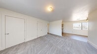 Located at 4801 Iowa in Las Vegas, NV, this two-bedroom, one-bathroom unit offers a clean, functional layout across a single floor. The living room is generously proportioned, featuring soft neutral carpet, crisp white walls, and a large window fitted with vertical blinds that allows natural light to fill the space. The area flows seamlessly toward the kitchen, which is visible in the background and features hard-surface flooring for easy maintenance.

Both bedrooms are carpeted and well-sized, each equipped with windows that bring in natural light. The primary bedroom is notably spacious and includes access to two closets, providing excellent storage. The second bedroom also features a window with vertical blinds and a dedicated closet. A hallway connects the bedrooms and leads to the full bathroom, which is outfitted with a tiled tub-shower surround in classic white square tile, a built-in shelf niche, and a small frosted window for ventilation and light. Additional storage is provided through multiple closets distributed throughout the unit. The overall aesthetic is clean, bright, and move-in ready, with a neutral color palette throughout.