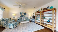 Located in Ocala, Florida, this single-floor home showcases a cohesive coastal-inspired aesthetic carried throughout each room. The generously sized living area serves as the heart of the home, featuring rich dark hardwood flooring, a textured ceiling, and a ceiling fan that enhances airflow and comfort. Natural light filters in through windows dressed with decorative valances, while a sliding glass door provides direct access to the outdoors. Open shelving units offer both storage and display space, complementing the relaxed, beach-themed decor.

The kitchen is well-appointed with ample white cabinetry, a full suite of appliances including a refrigerator, range, and dishwasher, all set atop matching hardwood-style flooring. Adjacent to the kitchen, the dining area benefits from a pendant chandelier overhead and a sliding glass door that opens to an exterior patio, bringing in natural light and outdoor views.

The bedroom is a calm retreat with neutral walls, carpeted flooring, and warm wood furnishings. The bathroom features a tub-shower combination and hardwood-style flooring, maintaining the home's consistent design language. Throughout, the space presents a warm, inviting atmosphere defined by its blue-and-green color palette and thoughtfully arranged interiors.