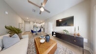 Located in Daytona Beach, FL, this thoughtfully designed one-bedroom, two-bathroom residence offers a functional and stylish single-floor layout. The open-concept kitchen flows seamlessly into the living and dining areas, creating a cohesive and efficient use of space. The kitchen is outfitted with crisp white cabinetry, a subway tile backsplash, granite countertops, stainless steel appliances, and a breakfast bar with pendant lighting — ideal for both cooking and casual dining. Light wood-style flooring runs throughout, enhancing the bright, airy atmosphere. The living room is anchored by large windows that invite natural light and feature a ceiling fan, sheer drapes, and direct access to an exterior door. The bedroom offers a serene retreat with a soft blue accent wall, generous window views of the outdoors, a ceiling fan, and access to the en-suite bathroom. The en-suite bath includes a granite-topped vanity, white cabinetry, and a soaking tub. A dedicated walk-in closet provides ample wire-rack storage. The second bathroom adds additional convenience. Neutral tones, recessed lighting, and clean modern finishes are consistent throughout, contributing to a cohesive and welcoming ambiance.