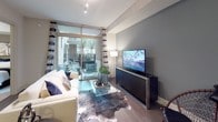 This well-appointed single-floor residence showcases a cohesive contemporary design with dark cabinetry, neutral tones, and quality finishes throughout. The gourmet kitchen is a standout feature, equipped with floor-to-ceiling dark shaker cabinets, gleaming quartz countertops, a large center island, stainless steel appliances including a French door refrigerator, electric range, built-in microwave, and dishwasher, all complemented by a classic white subway tile backsplash and warm wood-look flooring. Stylish pendant lighting adds a polished touch overhead.

The living area offers a comfortable and inviting atmosphere, highlighted by floor-to-ceiling glass doors that open to a private outdoor patio, flooding the space with natural light and providing seamless indoor-outdoor connectivity. The bedroom is generously sized with plush carpeting, a ceiling fan, and direct access to the en-suite bathroom. The primary bathroom is elegantly designed with a dual-sink vanity featuring rich dark cabinetry, white countertops, large framed mirrors, and a soaking tub set within a fully tiled surround. A separate half bathroom provides additional convenience. Throughout the residence, the interplay of dark and light tones, quality materials, and thoughtful layouts create a refined and functional living environment.