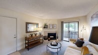 This well-appointed single-floor residence offers three bedrooms and two bathrooms across a thoughtfully designed layout. The living room serves as the heart of the home, featuring a corner fireplace with a tile surround and a sliding glass door that opens to a private balcony with outdoor views, allowing natural light to fill the space. Soft carpeting and a textured ceiling complete the comfortable, welcoming ambiance.

The galley-style kitchen is efficiently designed with rich dark wood cabinetry, granite-style countertops, a double-basin sink, and black appliances, including a range and refrigerator. Light wood-look flooring adds warmth to the space. Adjacent to the kitchen, the dining room features wainscoting detail, wood-look flooring, and access to a hallway closet, providing practical storage.

The bedrooms are carpeted and feature neutral walls with natural light from windows. The primary bedroom offers a generous footprint with ample room for furnishings. Both bathrooms are functional in design — one full bath includes a shower/tub combination with wood-look flooring and a single vanity, while the second bathroom provides a convenient half-bath configuration. A dedicated hallway and closet round out this efficient, comfortable layout.