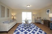 This single-floor residence offers a thoughtfully organized layout with distinct living, dining, kitchen, bedroom, and bathroom spaces. The living room serves as the focal point of the home, featuring rich hardwood-style flooring, a textured ceiling, and a large sliding glass door fitted with vertical blinds that invites natural light and provides outdoor views. The open feel of the room comfortably accommodates multiple seating areas.

Adjacent to the living room, a defined dining nook provides an intimate setting for meals, accented by a pendant light fixture overhead and hardwood-style flooring that continues from the main living area. The galley-style kitchen is efficiently designed with dark cabinetry lining both walls, providing ample storage, along with a stainless steel sink, countertop workspace, and black appliances including a refrigerator and electric range.

The bedroom offers a comfortable, carpeted retreat with a window dressed in vertical blinds for natural light and privacy. A walk-in closet adds practical storage. The bathroom is clean and functional, featuring a tub-shower combination, a vanity with a dark countertop, hardwood-style flooring, and classic white fixtures throughout.