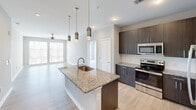 Located at 2120 N Brevard St in Charlotte, NC, this well-appointed 2-bedroom, 3-bathroom residence offers a thoughtfully designed single-floor layout with modern finishes throughout. The open-concept kitchen serves as the heart of the home, featuring a granite-topped center island with an undermount sink, sleek dark cabinetry, stainless steel appliances, and stylish pendant lighting. Light wood-style flooring flows through the main living and kitchen areas, creating a warm, cohesive aesthetic.

Both bedrooms are carpeted for comfort and include ceiling fans and large sliding windows that invite natural light and offer exterior views. The generously sized primary bedroom provides ample space for furnishings and includes direct access to a closet.

All three bathrooms are consistently finished with granite vanity countertops, dark wood cabinetry, large wall mirrors with modern lighting fixtures, and subway tile shower surrounds. Light wood-look flooring ties the bathrooms together with the rest of the home. One bathroom features a full soaking tub with a tiled surround, while others include walk-in style showers. The overall design emphasizes clean lines, neutral tones, and functional elegance throughout.