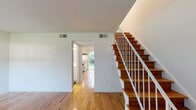 Located at 2101 Gorman St in Raleigh, NC, this two-story home offers a well-organized layout split evenly across two floors. Warm hardwood flooring flows throughout the main living areas and bedrooms, complemented by rich slate-style tile in the kitchen and bathrooms, creating a clean contrast of materials.

The main floor opens into a bright living room with natural light streaming through large windows that overlook greenery outside. A staircase with warm wood treads and white balusters connects both levels. The combined kitchen and dining area is equipped with white cabinetry, light countertops, a full suite of white appliances, and a window above the sink providing natural light. One bathroom on this floor doubles as a laundry room, housing a full-size washer and dryer alongside a vanity and toilet — a practical and space-efficient design.

Upstairs, two bedrooms offer comfortable proportions, with the spacious primary bedroom providing ample room for furnishings. Both bedrooms feature ceiling fans with light kits and natural light from windows. Closets are plentiful throughout, with four total across the home. A clean, bright full bathroom with a tub-shower combo, white vanity, and slate tile flooring serves the upper level. Utility needs are addressed by a dedicated mechanical room housing the HVAC system and water heater.