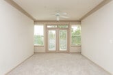 Located at 500 McDaniel St SW in Atlanta's Grant Park neighborhood, this single-floor residence offers a well-organized layout designed for comfortable everyday living. The open living area is finished with plush wall-to-wall carpeting and features a ceiling fan, crown molding detail, and access to an outdoor balcony through glass doors that bring in generous natural light. A pendant-lit dining area connects seamlessly to the kitchen, which is outfitted in a galley configuration with warm honey-toned cabinetry, dark countertops, a tile floor, and a full suite of white appliances including a refrigerator and electric range. A dedicated pantry door adds practical storage. The bedrooms are carpeted and bright, each equipped with a ceiling fan and windows fitted with horizontal blinds that frame views of surrounding greenery. One bedroom benefits from direct access to a private bathroom. Both bathrooms feature tiled tub-shower combinations with chrome fixtures; one is appointed with wood-look vinyl flooring and a vanity with warm wood cabinetry, while the other presents a clean, minimal design. Throughout the unit, neutral wall tones create a cohesive and understated aesthetic that provides a versatile backdrop for a variety of interior styles.