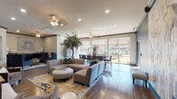 This single-story community clubhouse in Bentonville, Arkansas is thoughtfully designed to offer a variety of functional and welcoming spaces. The entrance foyer sets an elegant tone with exposed dark beams, hardwood flooring, a vibrant floral area rug, and a decorative console table topped with a large round mirror. Adjacent to the entry, a leasing office features soaring ceilings with bold beam detailing, teal accent chairs, and wall-mounted artwork, creating a professional yet approachable atmosphere.

The expansive main lounge area is anchored by a large sectional sofa, colorful area rug, and a statement indoor tree, all bathed in natural light from floor-to-ceiling sliding glass doors that open to outdoor views. A cozy media lounge with a deep teal accent wall, large flat-screen TV, and curated artwork offers a more intimate gathering space, while a tucked-away seating nook with navy wingback chairs provides a quiet retreat.

The kitchenette is well-appointed with dark cabinetry, granite countertops, stainless steel appliances, and a double sink. A dedicated business center with granite-topped workstations and computer terminals is conveniently positioned adjacent to a fitness facility, completing this comprehensively amenitized space.