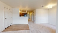 This single-floor unit offers a practical and cohesive layout designed for comfortable everyday living. The entry opens into a spacious living area finished with light wood-look flooring that transitions into plush neutral carpeting, creating a warm and inviting atmosphere. A half-wall peninsula separates the living space from the kitchen, which features a galley-style configuration with rich dark cabinetry, laminate countertops, a double-basin sink, and black appliances including a refrigerator and range. Pendant lighting above the peninsula and a flush ceiling fixture provide functional illumination throughout.

The bedrooms are carpeted and well-proportioned, each with windows fitted with blinds that allow natural light while maintaining privacy. One bedroom benefits from an exterior door providing direct outdoor access, while another overlooks a neighboring streetscape. The bathrooms are finished with wood-look vinyl flooring, dark vanity cabinetry with light countertops, and tub-shower combinations with tiled surrounds and chrome fixtures. Grab bars are present in one bathroom, offering added accessibility. The overall color palette remains neutral throughout, contributing to a clean and cohesive aesthetic.