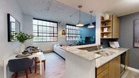 Located at 40 Locke St in Haverhill, MA, this one-bedroom, one-bathroom loft-style residence blends industrial character with contemporary design. The open-plan layout connects the kitchen, dining, and living areas into a cohesive, light-filled space anchored by dramatic floor-to-ceiling factory-style windows with black frames that flood the interior with natural light and offer views of the surrounding streetscape.

The kitchen features granite countertops, warm wood cabinetry, a tile backsplash, stainless steel sink, and a peninsula that doubles as a breakfast bar — seamlessly connecting to the dining and living areas. A bold teal accent wall grounds the living room, which is characterized by soaring ceilings with an exposed, textured industrial finish and stylish pendant lighting.

The bedroom is a serene retreat with the same expansive factory windows, light wood flooring, and access to two closets, providing ample storage. The bathroom is clean and functional, finished with white subway tile in the tub/shower surround, light wood-style flooring, and dark gray walls for a modern contrast. Light wood flooring runs throughout the entire unit, unifying the space with warmth and cohesion.