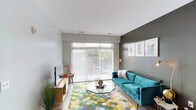 This single-floor residence combines modern design with functional living across several well-defined spaces. The living room serves as a welcoming focal point, featuring large sliding glass doors that flood the room with natural light and provide views of the outdoors. A bold accent wall in dark grey anchors the space, complementing the light flooring that runs throughout the common areas.

The kitchen is thoughtfully designed with rich dark-wood cabinetry, white countertops, and a full suite of black appliances, including a refrigerator, range, microwave, and dishwasher. A butcher-block island with seating provides a casual dining option, while pendant lighting and track lights enhance both style and functionality. Ample upper and lower cabinet storage adds practicality.

The two bedrooms are carpeted and naturally lit through window blinds, offering a quiet, comfortable atmosphere. Each has access to its own bathroom, both finished with dark-wood vanities, white countertops, and wood-look flooring. One bathroom features a shower-tub combination, while the other includes a tub with a striped curtain.

A dedicated utility closet houses a stacked washer and dryer alongside a water heater, providing convenient in-unit laundry. The overall aesthetic is cohesive, modern, and practical.