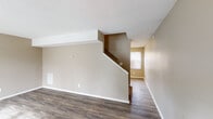 This two-story home offers a practical and straightforward layout across both levels. The main floor features durable hardwood-style flooring throughout the open living area, which is bathed in natural light from windows dressed with vertical blinds. A staircase with a classic wood railing connects the two floors, adding a sense of vertical flow to the space. The kitchen is well-equipped with light wood cabinetry offering ample storage, dark laminate countertops, a stainless steel electric range, and a double basin sink positioned beneath a window. A convenient bathroom on this level includes a vanity with a mirrored medicine cabinet and a tub/shower combination with clean white surround panels. Upstairs, the bedrooms are finished with plush carpeting in a warm neutral tone and feature ceiling fans with light fixtures. Each room benefits from natural light through windows with vertical or horizontal blinds. The bedrooms provide generous proportions and closet access, creating comfortable and versatile living spaces. Throughout the home, warm beige and taupe tones create a cohesive, neutral palette. Textured ceilings, crisp white trim, and consistent flooring choices contribute to a clean, move-in-ready aesthetic across both floors.