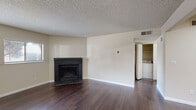 Located at 8965 E Florida Ave in Denver, Colorado, this single-floor residence offers a well-organized layout designed for comfortable everyday living. The living room serves as the heart of the home, showcasing rich dark hardwood-style flooring, a classic brick fireplace, and windows that invite natural light into the space. A pass-through kitchen counter connects the living area to the galley-style kitchen, which is outfitted with dark espresso cabinetry, light stone-look countertops, stainless steel appliances including an electric range and refrigerator, a dishwasher, and an overhead range hood. The kitchen's efficient corridor layout maximizes storage and counter workspace. Bedrooms feature neutral wall tones and plush carpeting, offering a calm and restful atmosphere, with windows providing additional natural light. The bathroom includes a full tub and shower combination with clean white tile surround and chrome fixtures. A dedicated in-unit laundry closet with louvered doors houses a full-size washer and dryer, adding everyday convenience. Textured ceilings are consistent throughout the unit. The overall design is clean and functional, with a neutral palette that provides a versatile canvas for personalization.