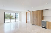 This contemporary apartment in Coral Gables offers 1050 square feet of thoughtfully designed living space. The open-concept layout showcases a sleek kitchen with two-toned cabinetry, featuring warm wood lower cabinets and crisp white upper units. High-end appliances, including a built-in oven and microwave, complement the stylish design.

The living area is bathed in natural light, thanks to floor-to-ceiling sliding glass doors that lead to a private balcony. This outdoor space provides lush views of the surrounding greenery and cityscape. Both bedrooms are generously sized, with the primary bedroom boasting 200 square feet of space.

Two well-appointed bathrooms feature modern fixtures, including floating vanities and glass-enclosed showers. The apartment's neutral color palette, highlighted by light tile flooring throughout, creates a bright and airy atmosphere. Recessed lighting and elegant ceiling fixtures add to the overall ambiance.

Storage is ample, with a dedicated closet space and built-in cabinetry in the kitchen. The property's location at 701 Valencia Ave in Coral Gables puts residents in the heart of this desirable Florida community. With its blend of style, comfort, and location, this apartment offers a premium living experience in a sought-after area.