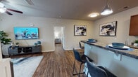 Located at 3502 Jenks Ave in Panama City, Florida, this single-story residence offers a well-designed layout with a cohesive, modern aesthetic throughout. Rich wood-look vinyl flooring flows seamlessly across the living, dining, kitchen, and bedroom areas, lending warmth and visual continuity to the entire space.

The open-concept living and dining area is bright and welcoming, with a bar-height countertop peninsula separating it from the kitchen and providing additional seating. Pendant lighting above the bar and flush-mount ceiling fixtures illuminate the space, while contemporary abstract artwork adds a stylish touch. A dedicated dining nook accommodates a round glass table, creating a defined yet intimate area for meals.

The galley-style kitchen features warm wood cabinetry, granite-look countertops, a full suite of black appliances including an electric range and refrigerator, and a sink with ample counter space. A doorway at the end of the kitchen leads directly to a dedicated in-unit laundry room equipped with a full-size washer and dryer.

The bedrooms are comfortably proportioned, each featuring ceiling fans, wood-look flooring, and generous closet space — including a walk-in closet in one bedroom. Two full bathrooms serve the unit: one with a dual-sink vanity and shower, and another with a single vanity and a tub-shower combination, both finished with granite-look countertops and wood cabinetry.